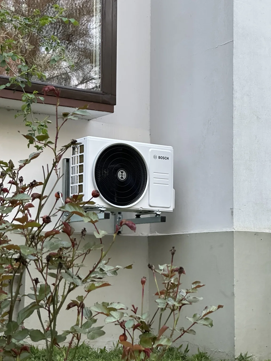 Außengerät einer Klimaanlage vor Pflanzen